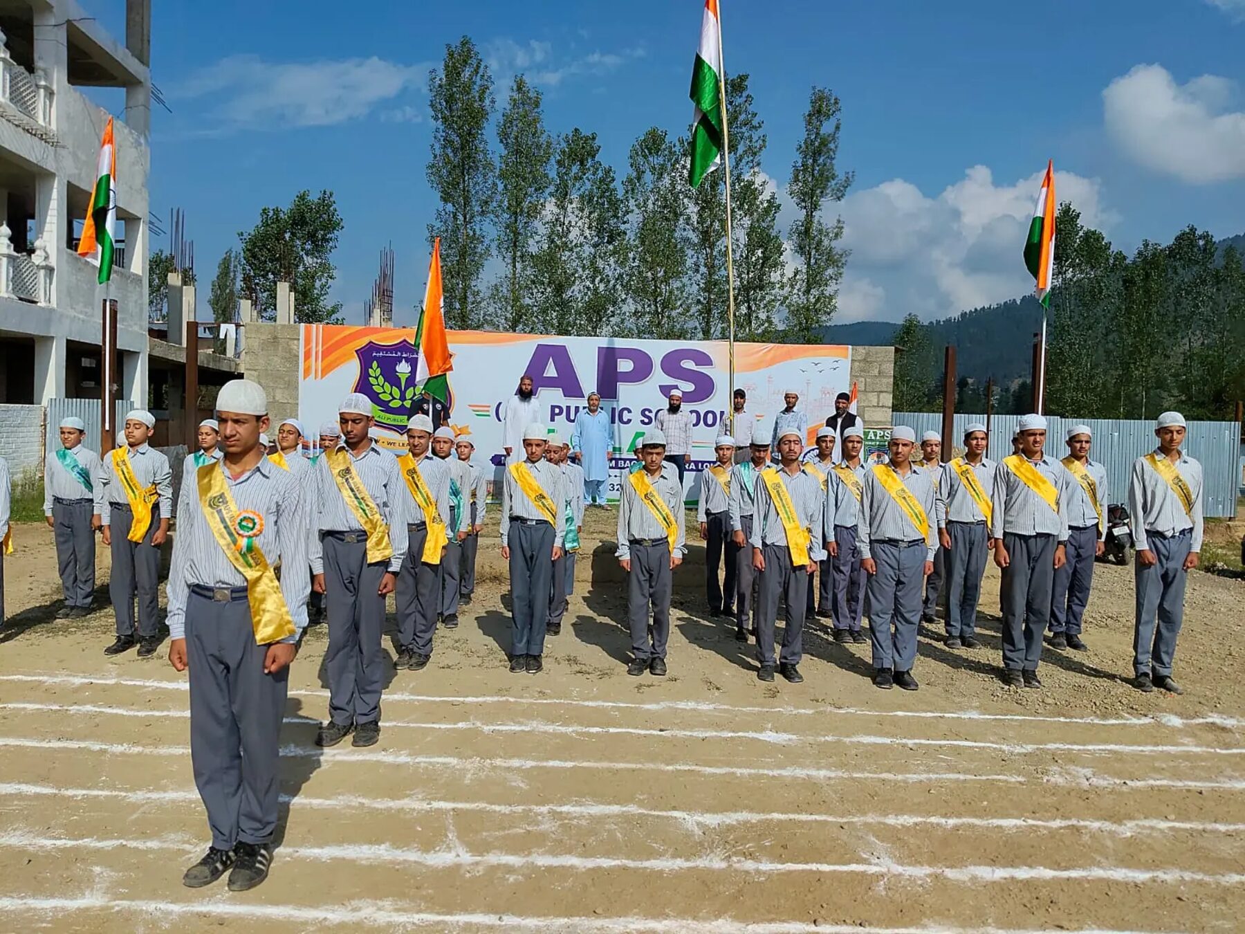 Students with sashes lined up for a school parade on the ground.