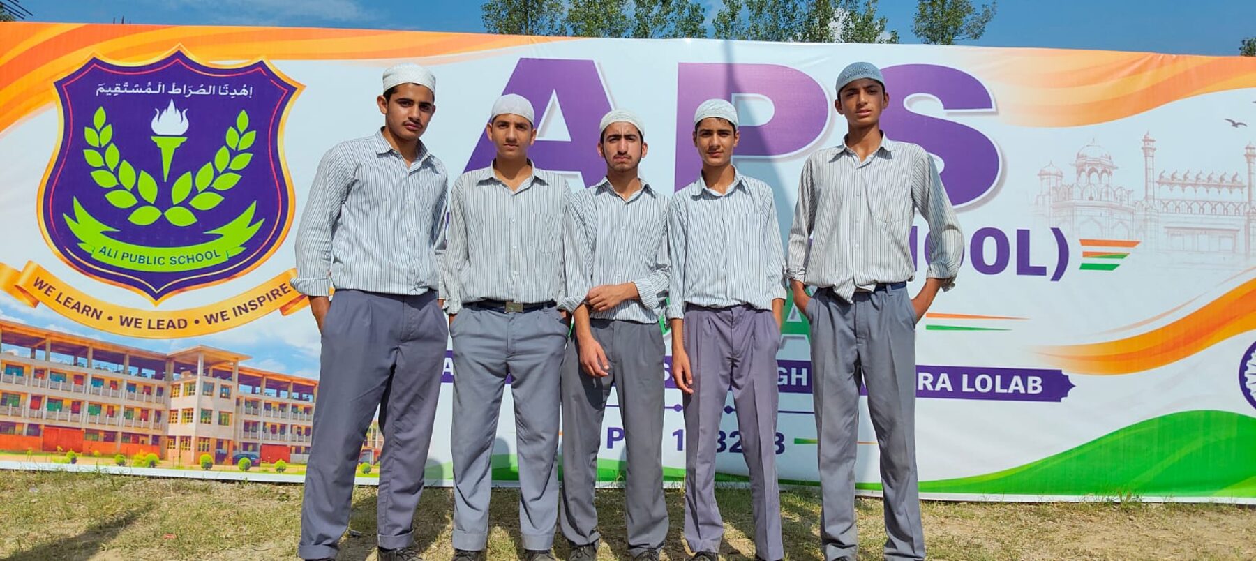 Senior boys of APS Lolab in front of the school banner.